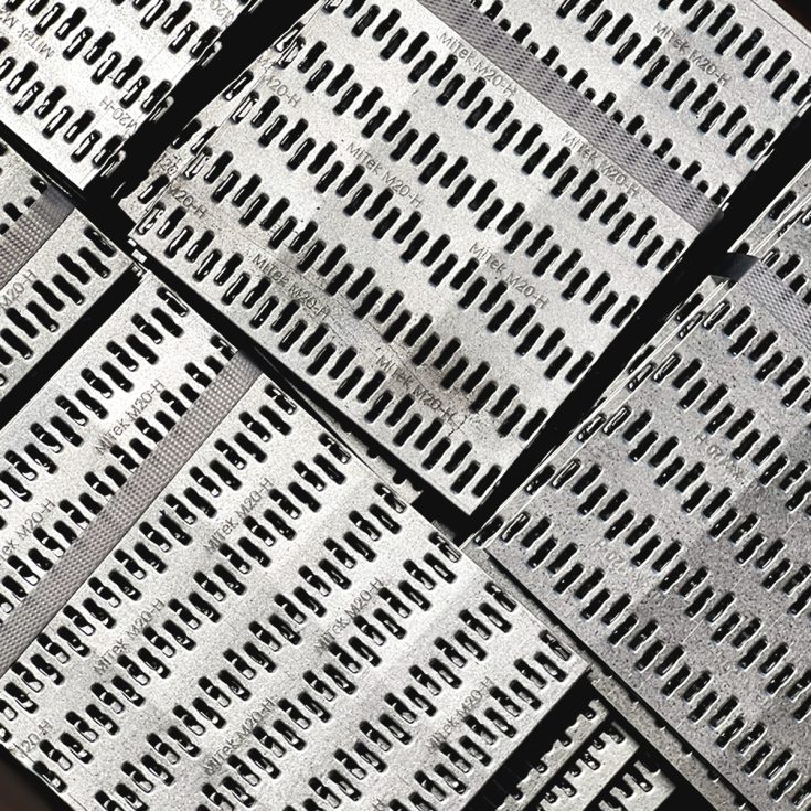 Didelis kiekis cinkuoto plieno dygliuotų plokštelių, paruoštų medinių santvarų gamybai.